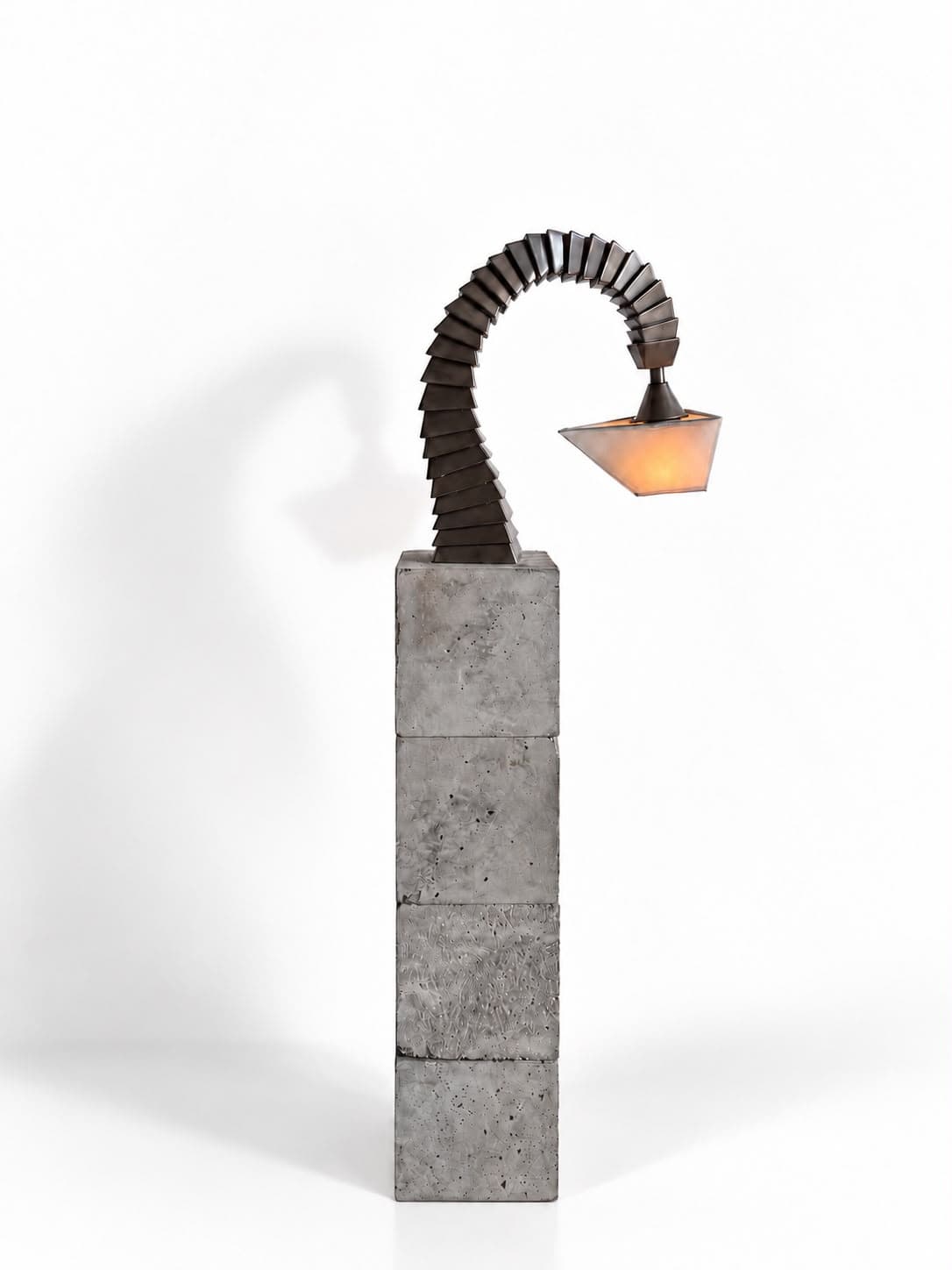 The same lamp square on, the arch of plates reading as one sweep from the plinth to the shade hanging clear of it, the concrete faces pitted and mottled