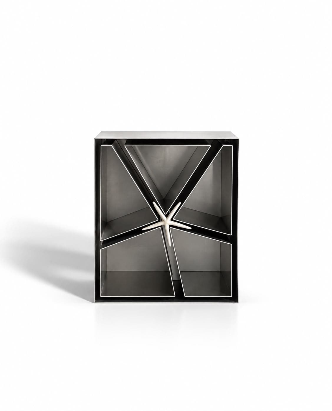 A dark steel cube open at the front, its interior divided by diagonal blades that radiate from a polished six-armed star at the centre