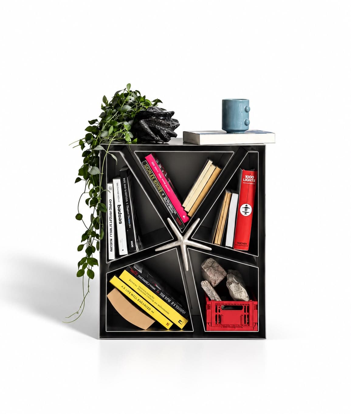 The same cube in use, its wedge-shaped compartments filled with books, with a plant, a stone and a mug resting on top