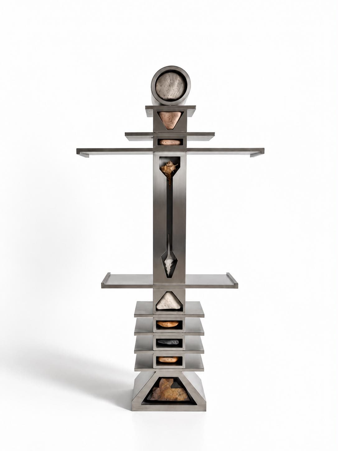 A standing steel totem: a round drum at the top like a head, a flat shelf arm to each side, and a shaft of stacked trays over a triangular base, with rock set in lit windows down the centre