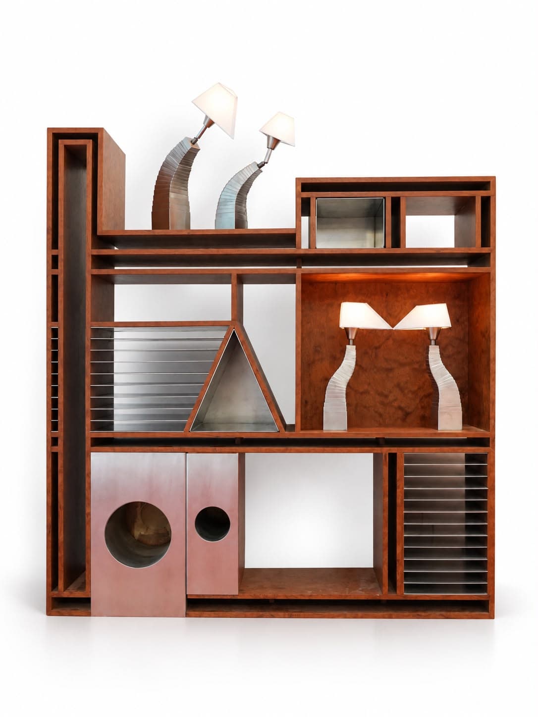 A tall rosewood unit of unequal compartments, standing slightly taller than it is wide: a narrow open frame runs the full height at the left, a bank of horizontal steel fins and a triangular steel tunnel fill the middle, a burl-backed bay holds two lamps on fluted steel stems, two rose-coloured metal boxes with round portholes sit at the foot, and two more curved lamps lean out over the top shelf